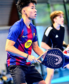 Zwei junge Männer stehen auf einem Padel-Court und erwarten den Ball