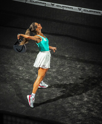 Frau mit langen Haaren steht auf dem Court und holt gerade mit ihrem Schläger aus