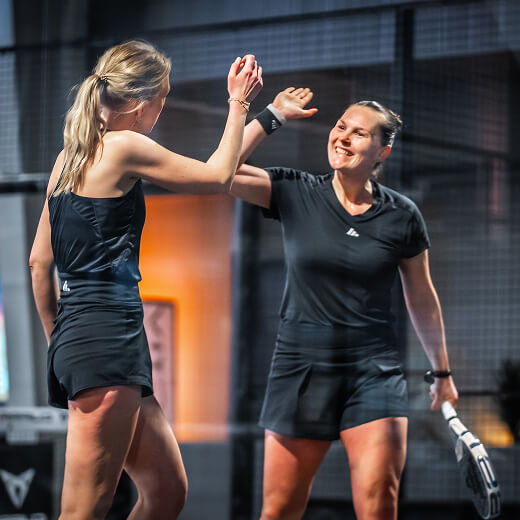 Zwei junge Frauen, ganz in schwarz gekleidet, klatschen sich auf dem Court ab